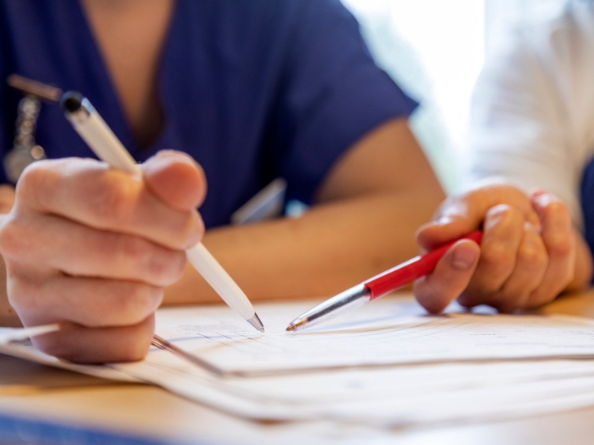 När bild på två personer som håller i pennor och pekar på ett papper.