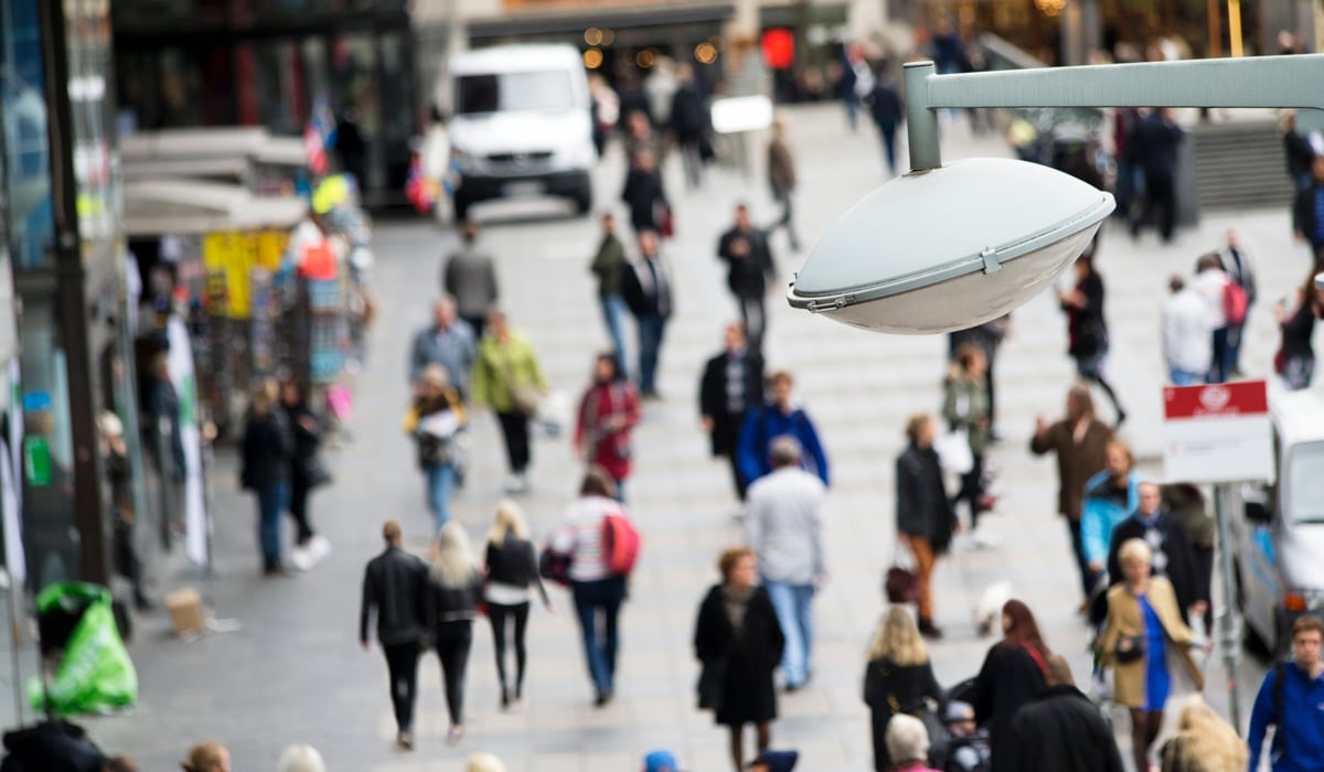 Bild över torg fullt av förbipasserande människor