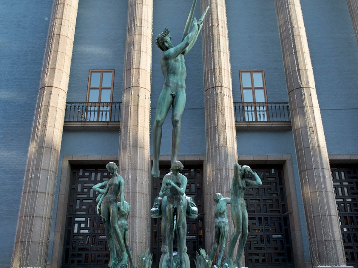 En staty av en man som står på toppen av en fontän framför en byggnad