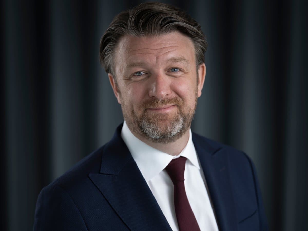 En man i kostym och slips poserar för en bild.