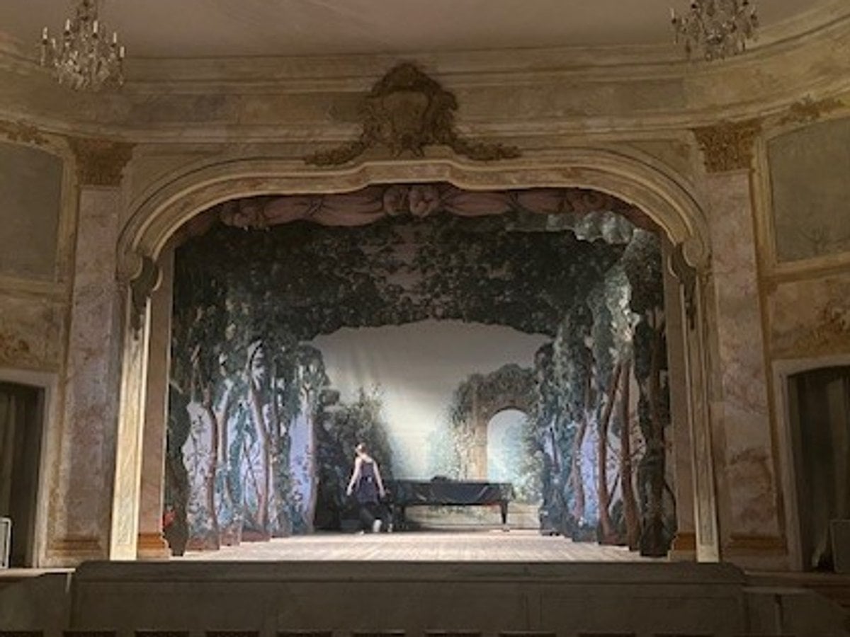 Scenrummet i Ulriksdals slottsteater. Stolar framför en scen i 1700-talsstil med kulisser och scenljus