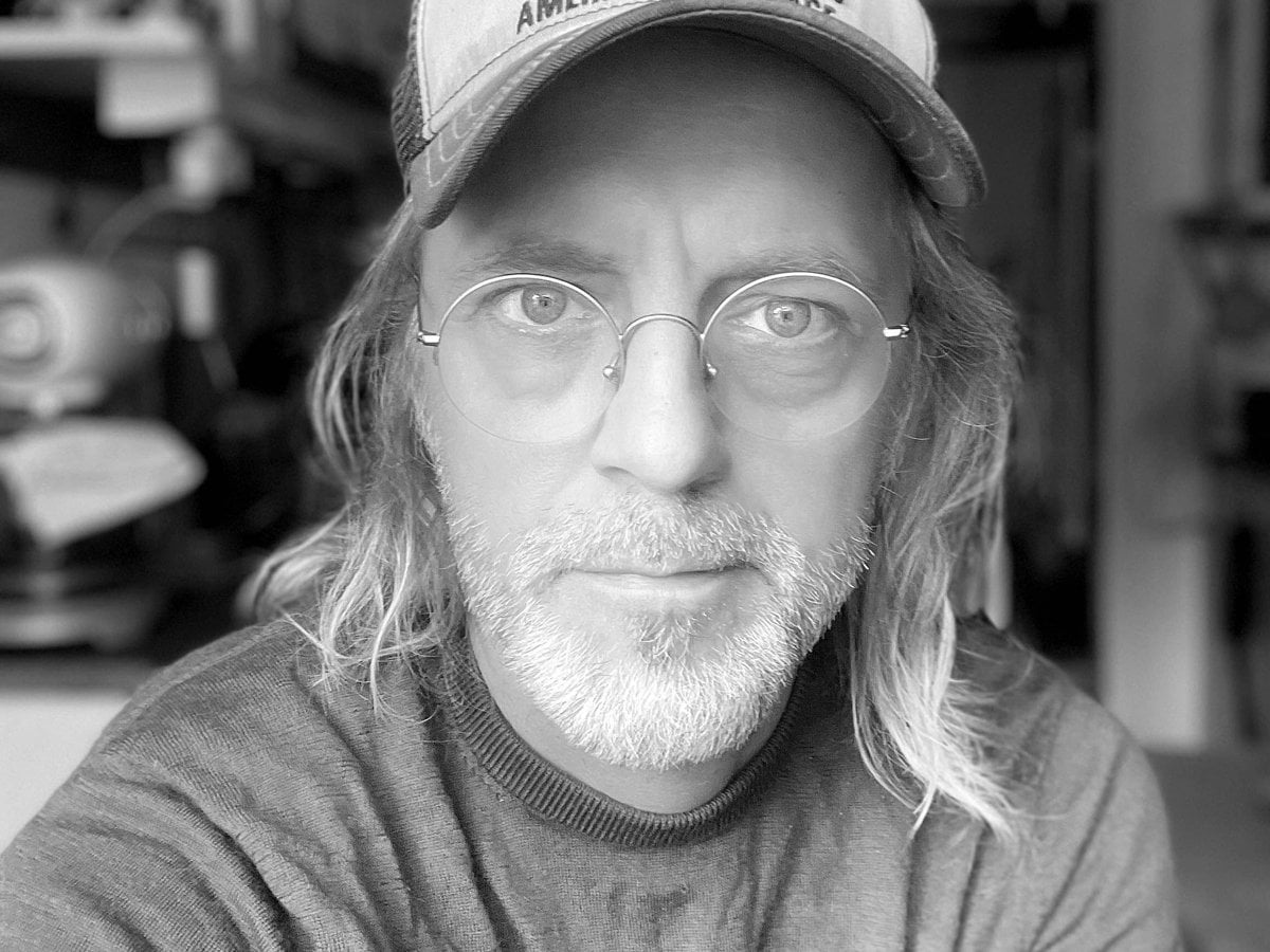 Johan har keps och glasögon. Svart-vitt foto från ateljén.