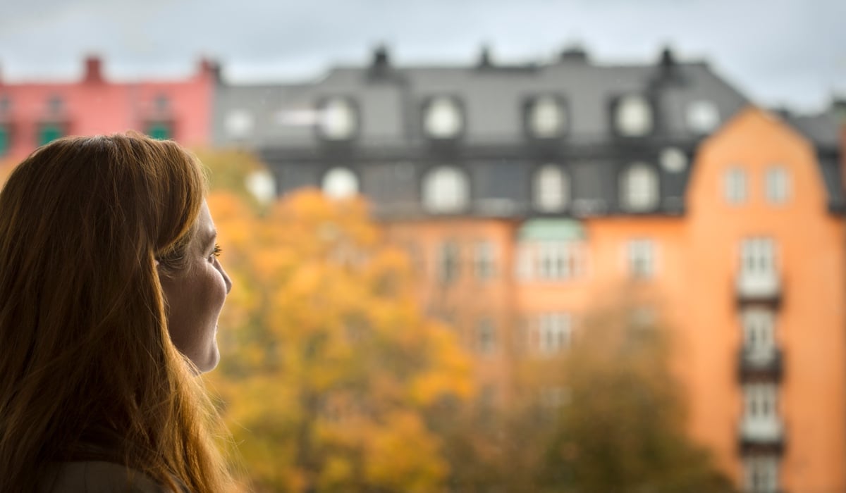 Bild på kvinna som blickar ut från fönster.