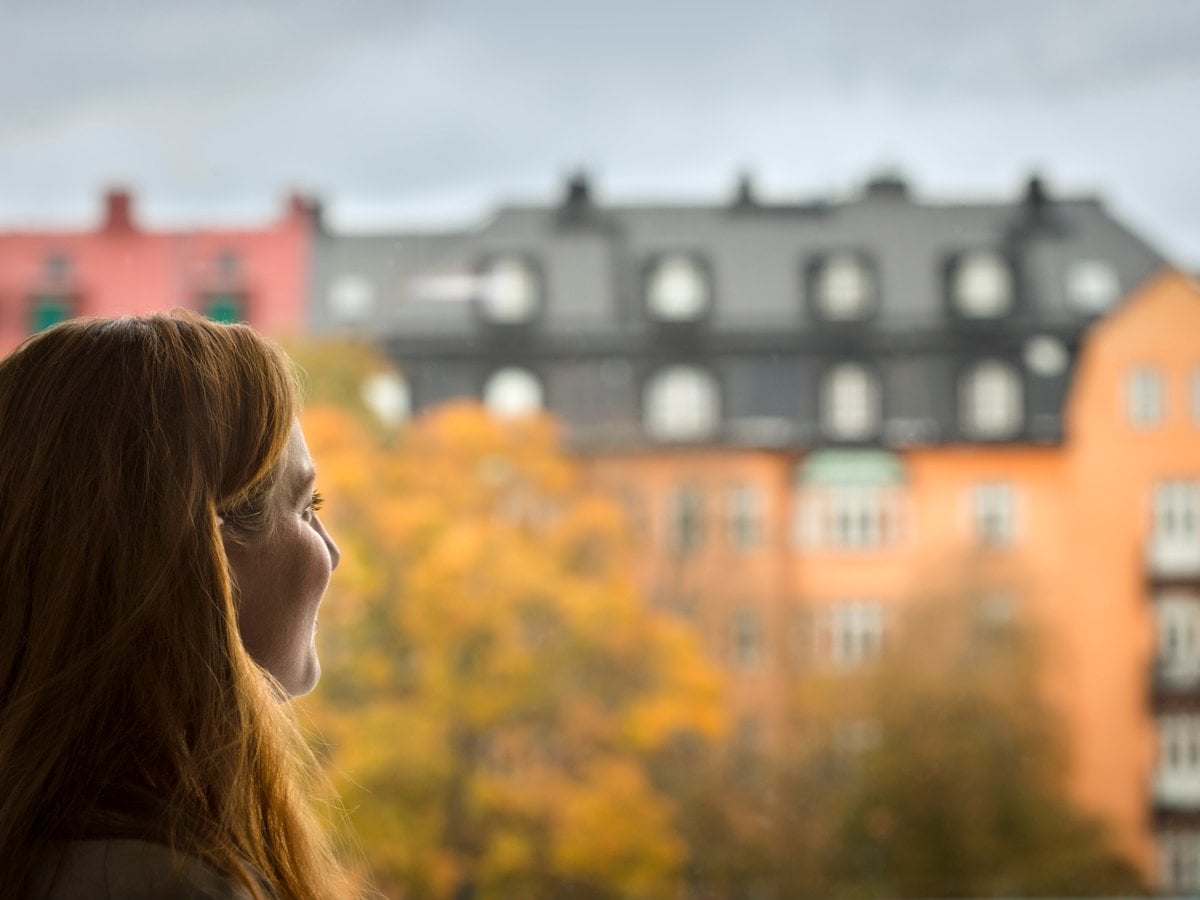 Bild på kvinna som blickar ut från fönster.