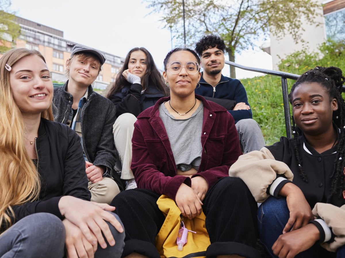 Sex ungdomar som sitter ned i trappa utomhus.