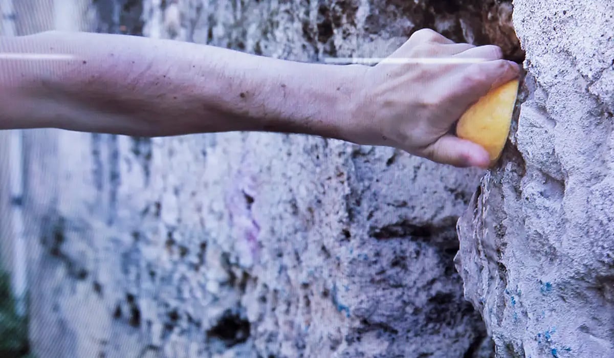 Hans som pressar en citron mot en skrovlig stenvägg.