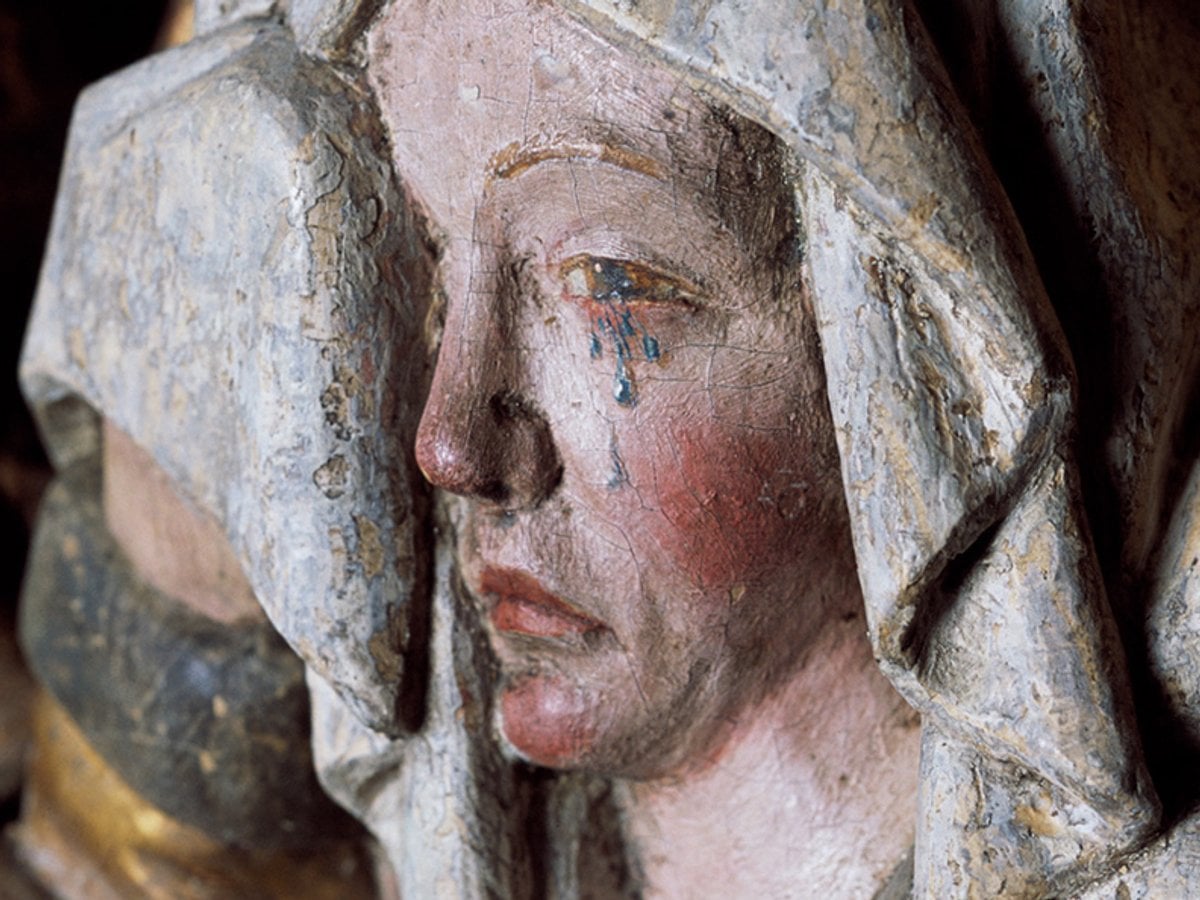 Bemålad träskulptur av en gråtande madonna.