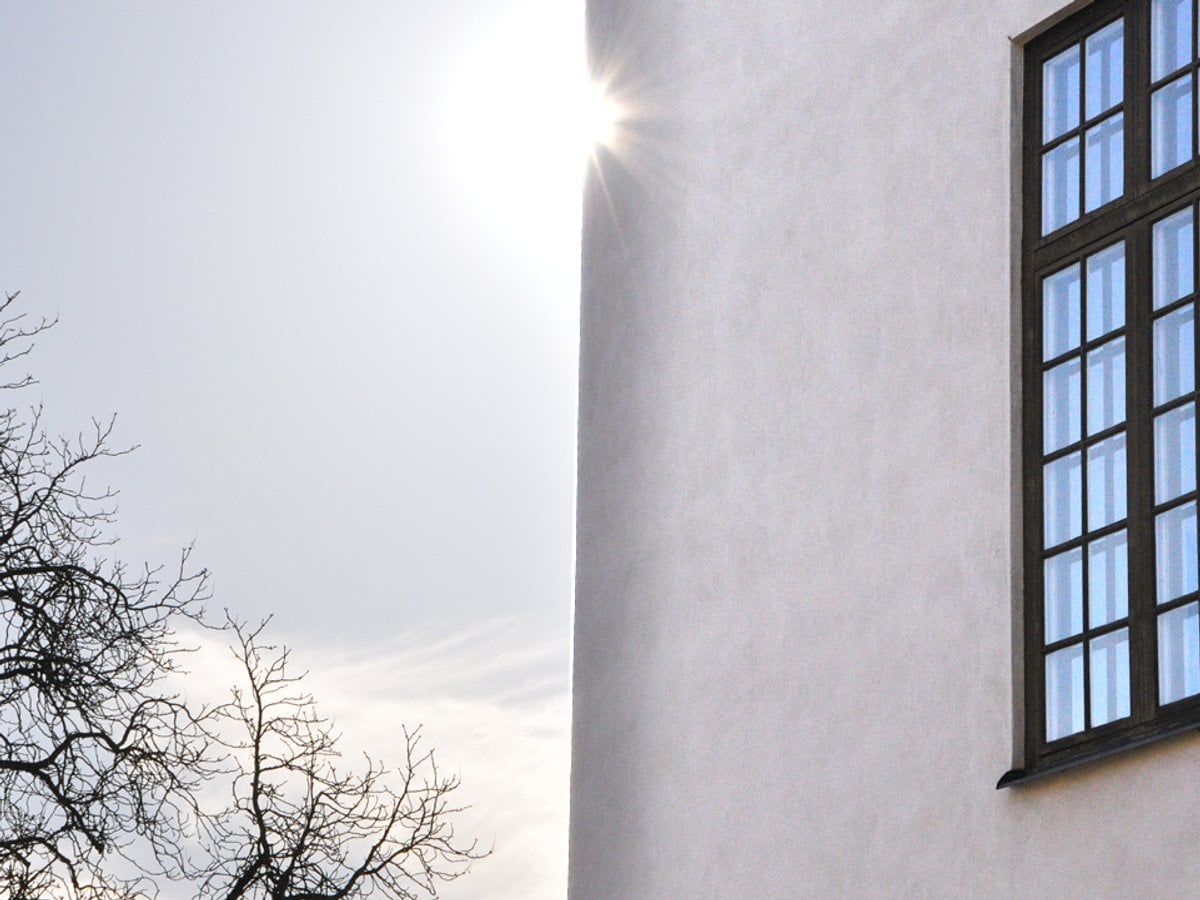 Bild på vacker husfasad där solen tittar fram runt husknuten.