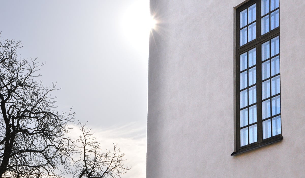 Bild på vacker husfasad där solen tittar fram runt husknuten.