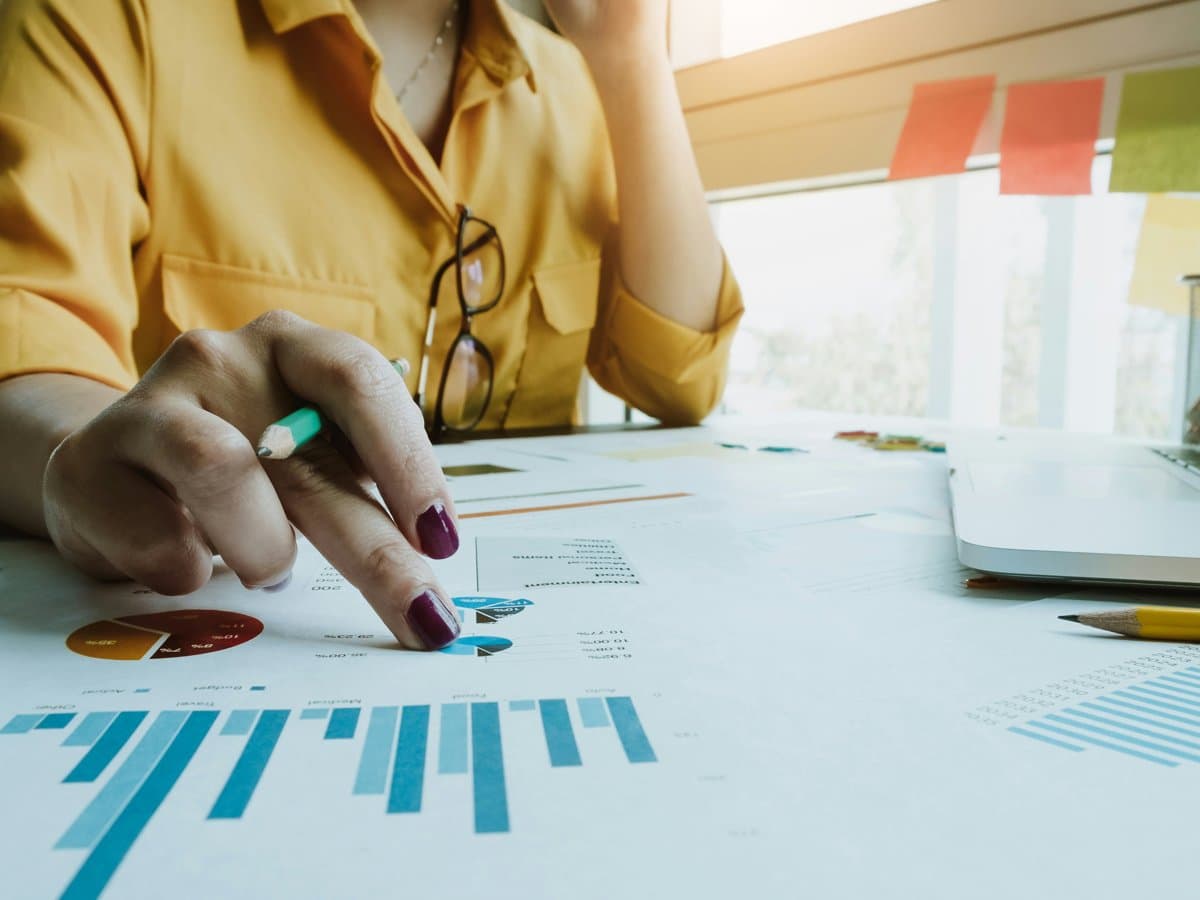 Närbild på hand som pekar på ett ark med tabeller.