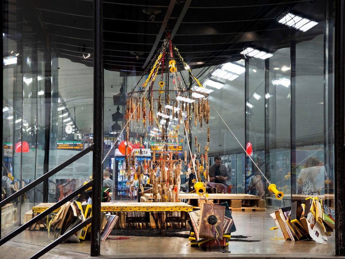 Installation i montern. Ljuskrona av skräp. Boktyngder som håller upp kronan.