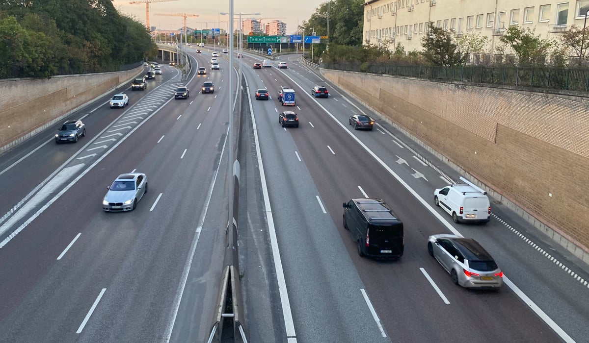 Bilar på en motorled genom bebyggelse.