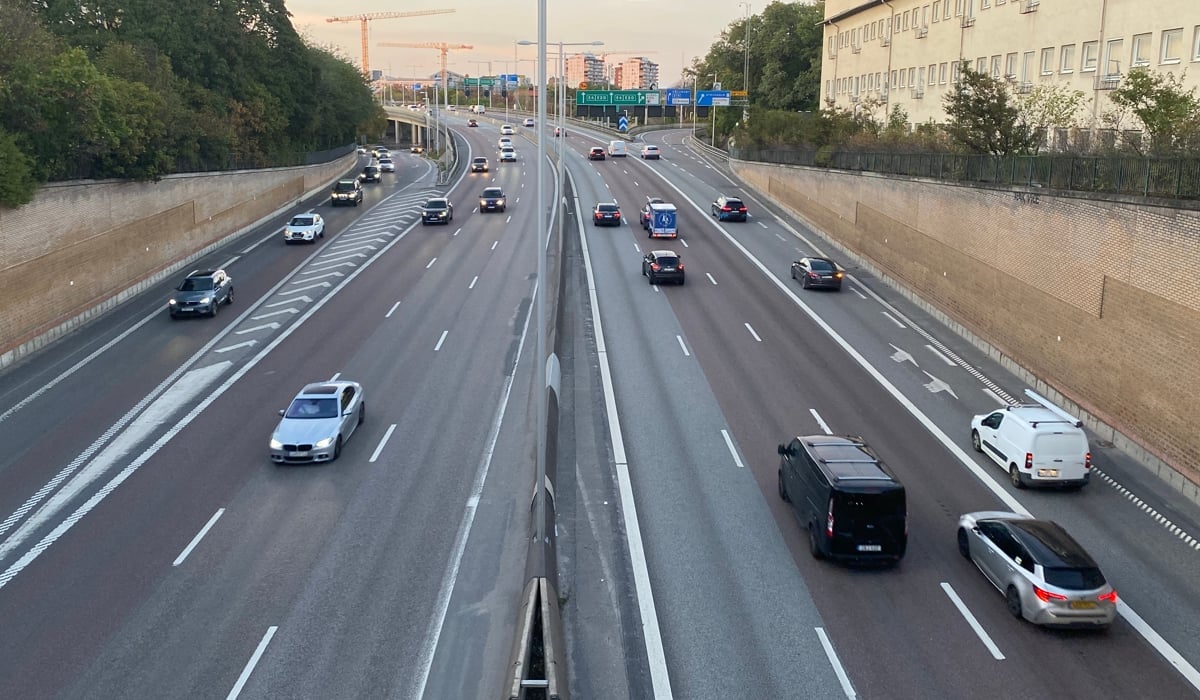 Bilar på en motorled genom bebyggelse.