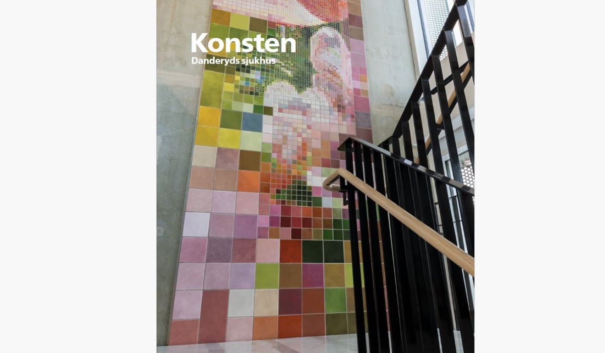 Vägg i trapphus klädd av kakelplattor i olika storlekar och färger. Vissa partier skapar mönster av blomblad.