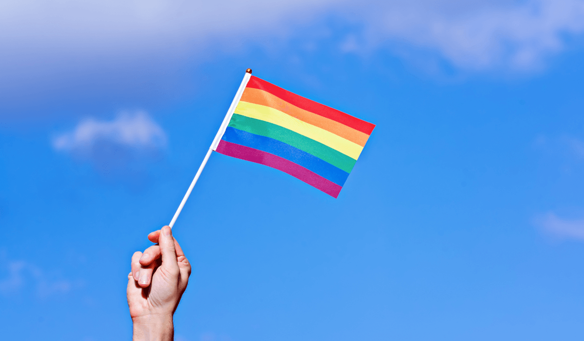 En hand håller i en prideflagga