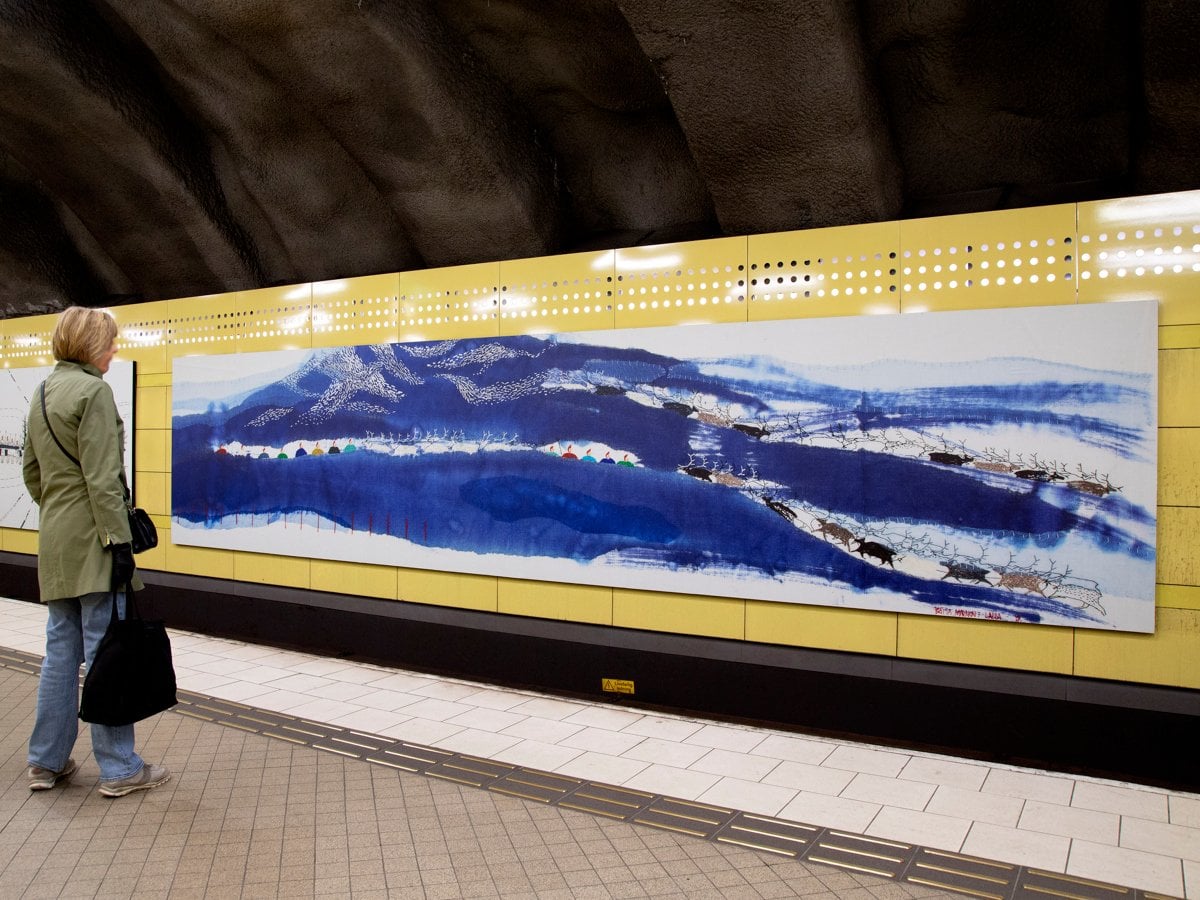 Lång tavla på Fridhemsplans tunnelbanestation. En kvinna står och tittar.