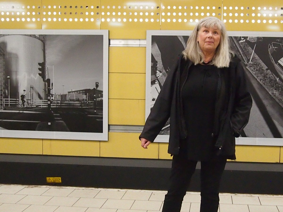 Martha såt på plattformen. I bakgrunden hennes uppförstorade fotografier av stadsmiljöer.