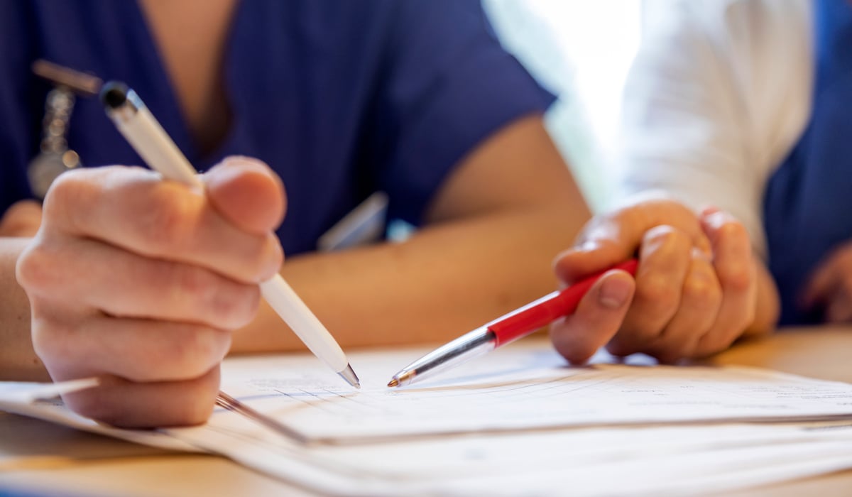 Bild över dokument liggande på ett bord, två personer tittar tillsammans på det och diskuterar sannolikt dess innehåll.