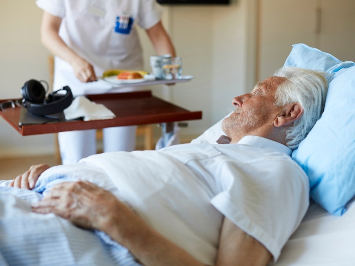 Man i sjukhussäng får mat.