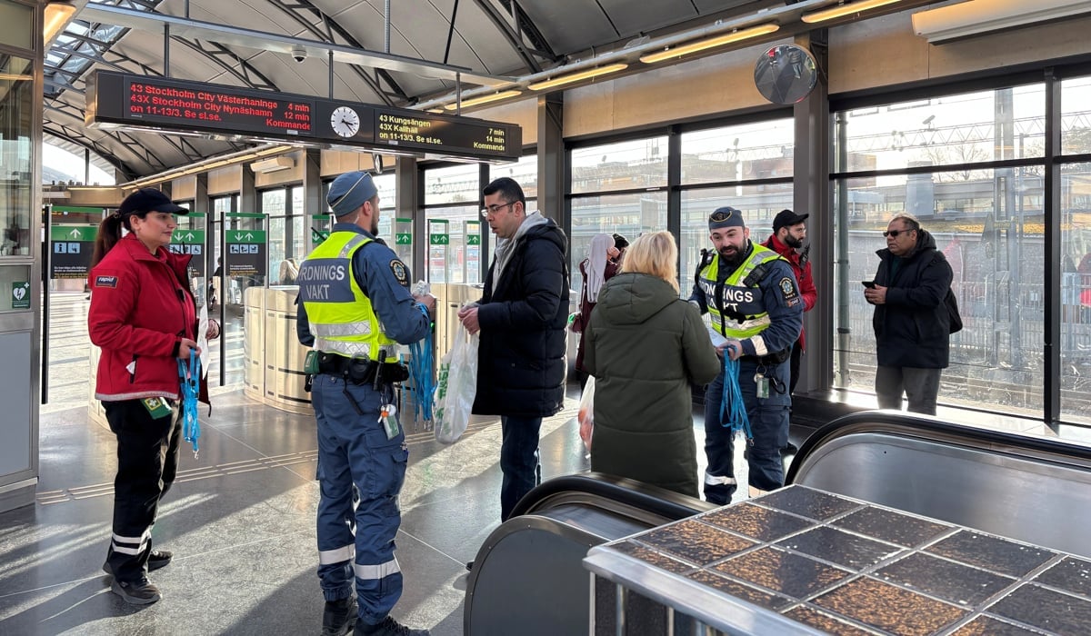 Trygghetsvakter och ordningsvakter står och pratar med folk på en pendeltågsstation
