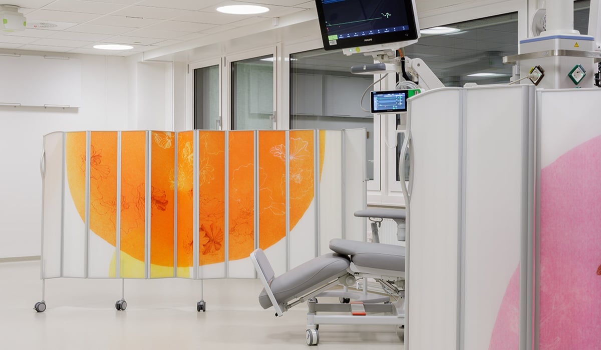 Undersökningsrum med avskiljande skärmar med motiv på.