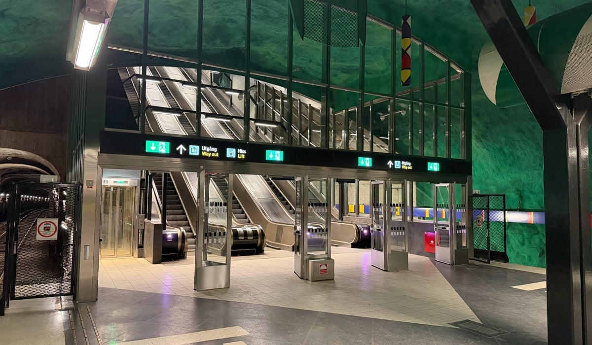 En tom tunnelbanestation med trappor och en grön vägg.