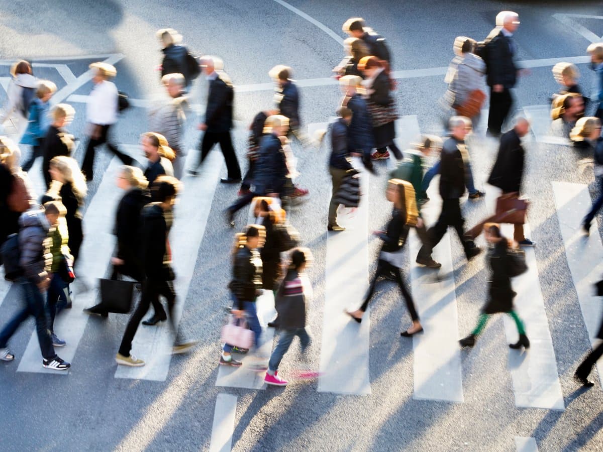 En stor grupp människor som korsar en gata.