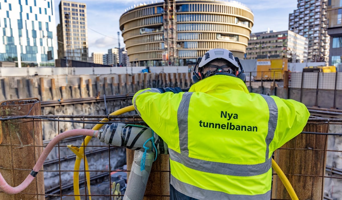 Foto av byggarbetare bakifrån med texten "Nya tunnelbanan" skriven på jackan