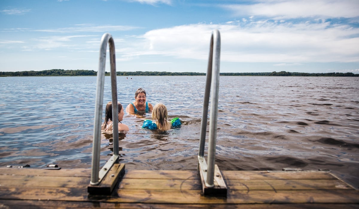 Bild tagen från bryggan på tre stycken som badar