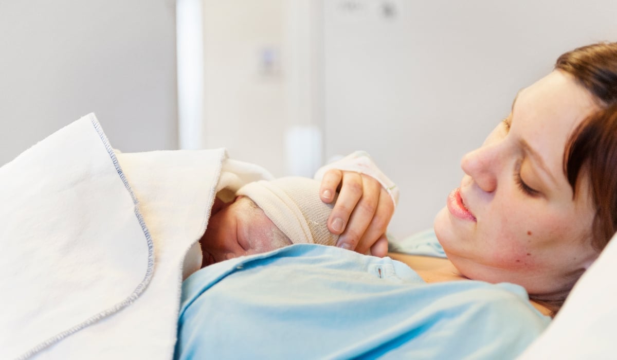 Kvinna med nyfödd bebis på bröstet