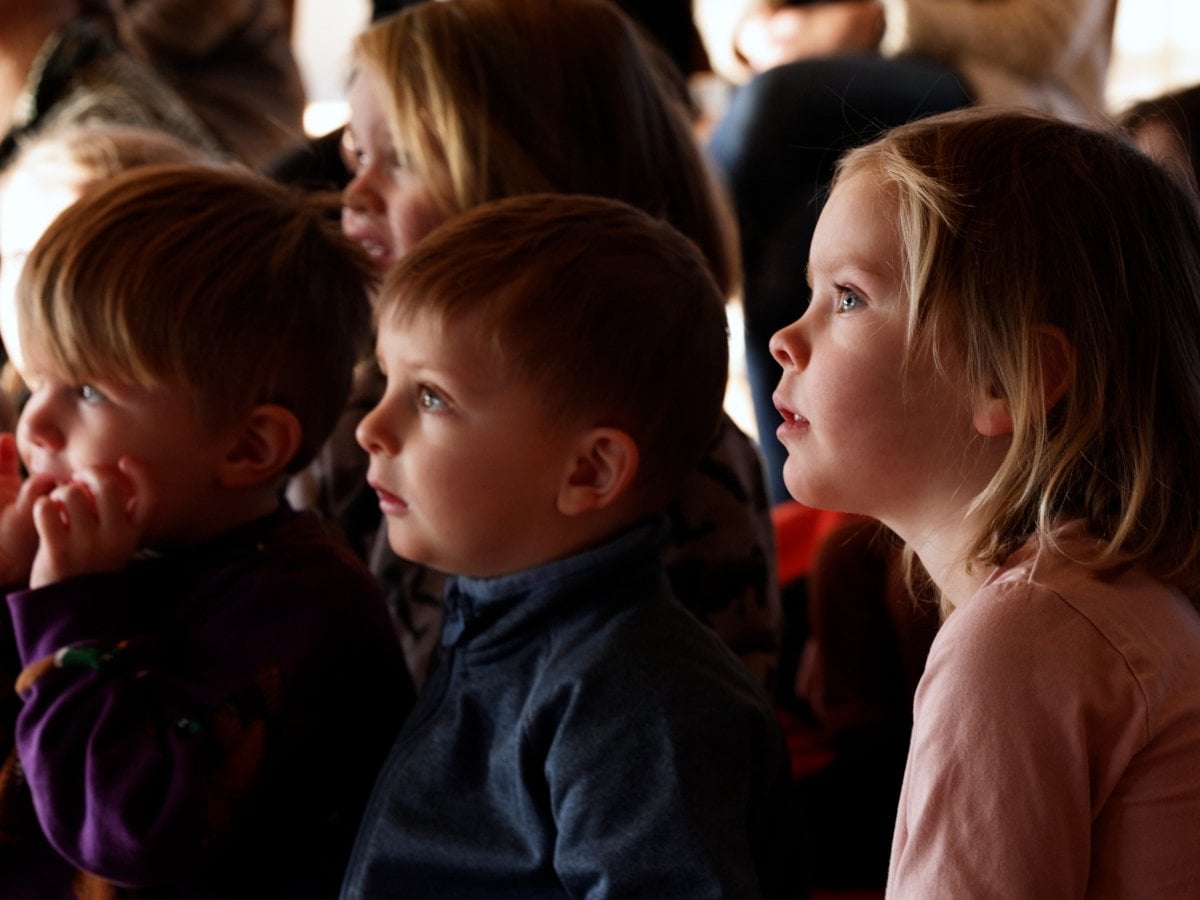 Barn som sitter och tittar koncentrerat åt samma håll (föreställningen de tittar på är utanför bilden)