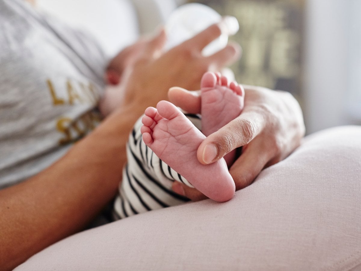 En bebis som matas med flaska i knä på förälder.