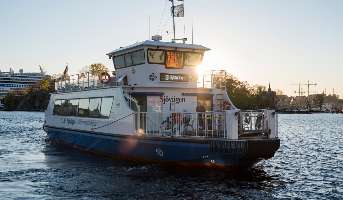 Pendelbåt i centrala Stockholm, solnedgång i bakgrunden och båten navigerar sig till sin destination