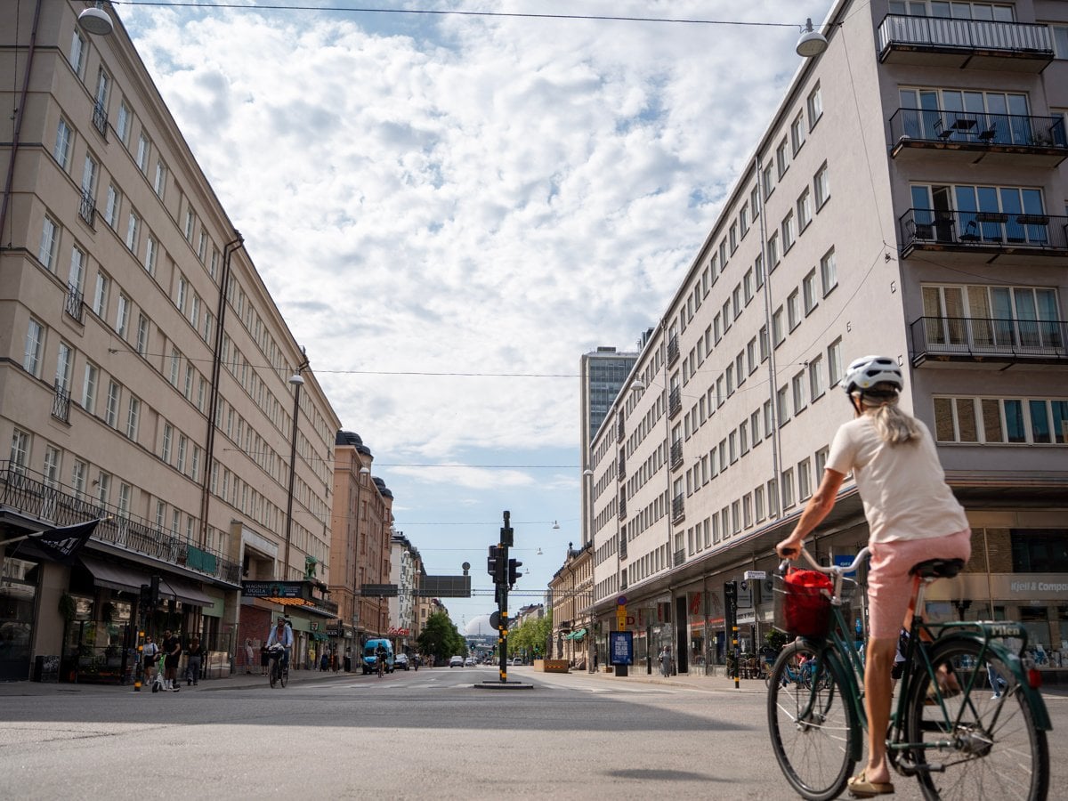 Gatuvy av Götgatan. En kvinna cyklar längs de höga byggnaderna utmed med gatan.
