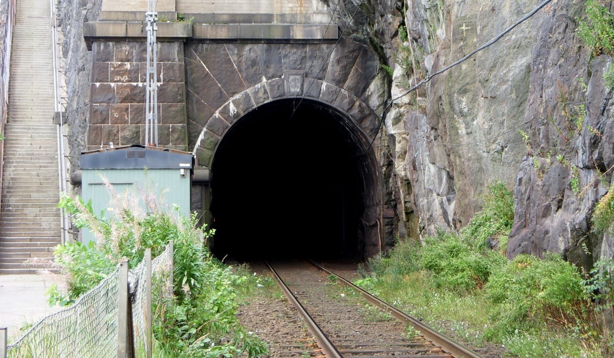 En spårvägstunnel med spår som kommer ut ur den.