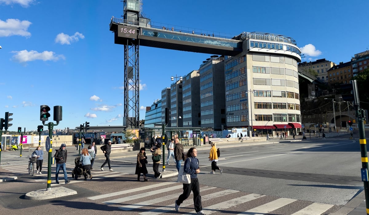 En grupp människor som korsar en gata framför en hög byggnad.