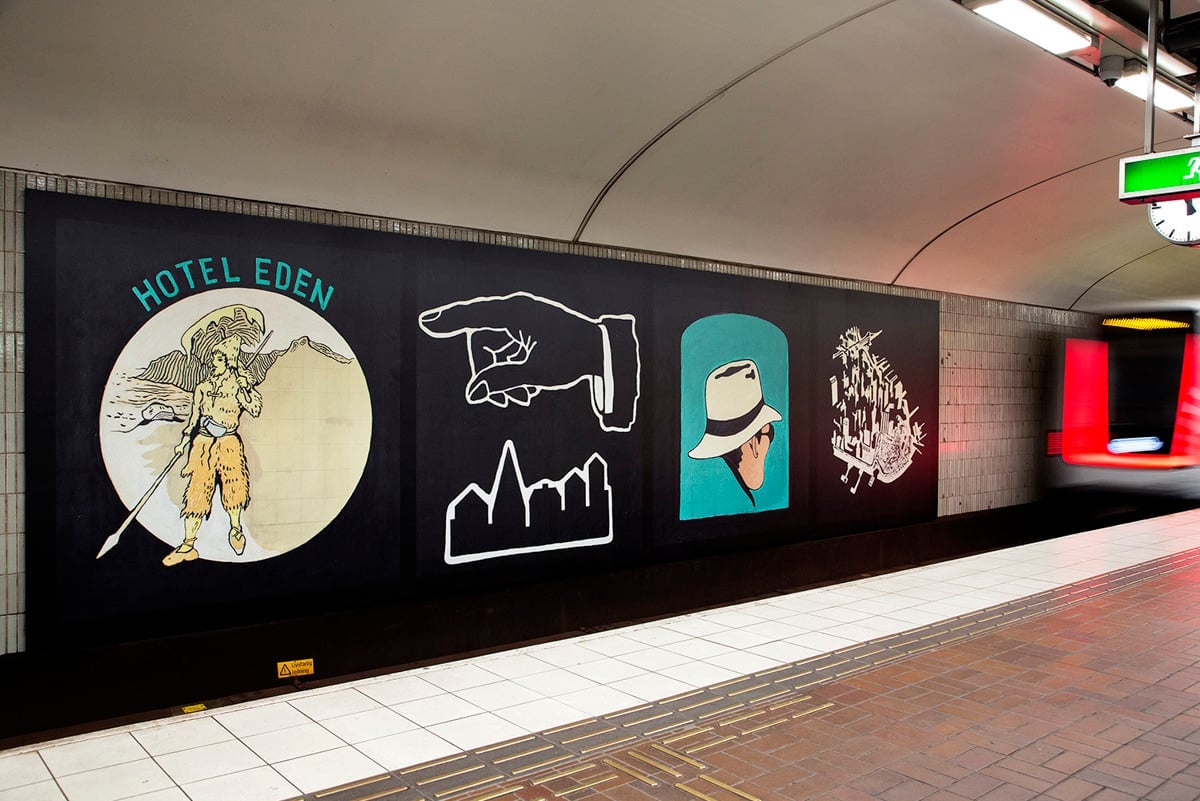 Lån bild utmed tunnelbanevägg med illustrationer.