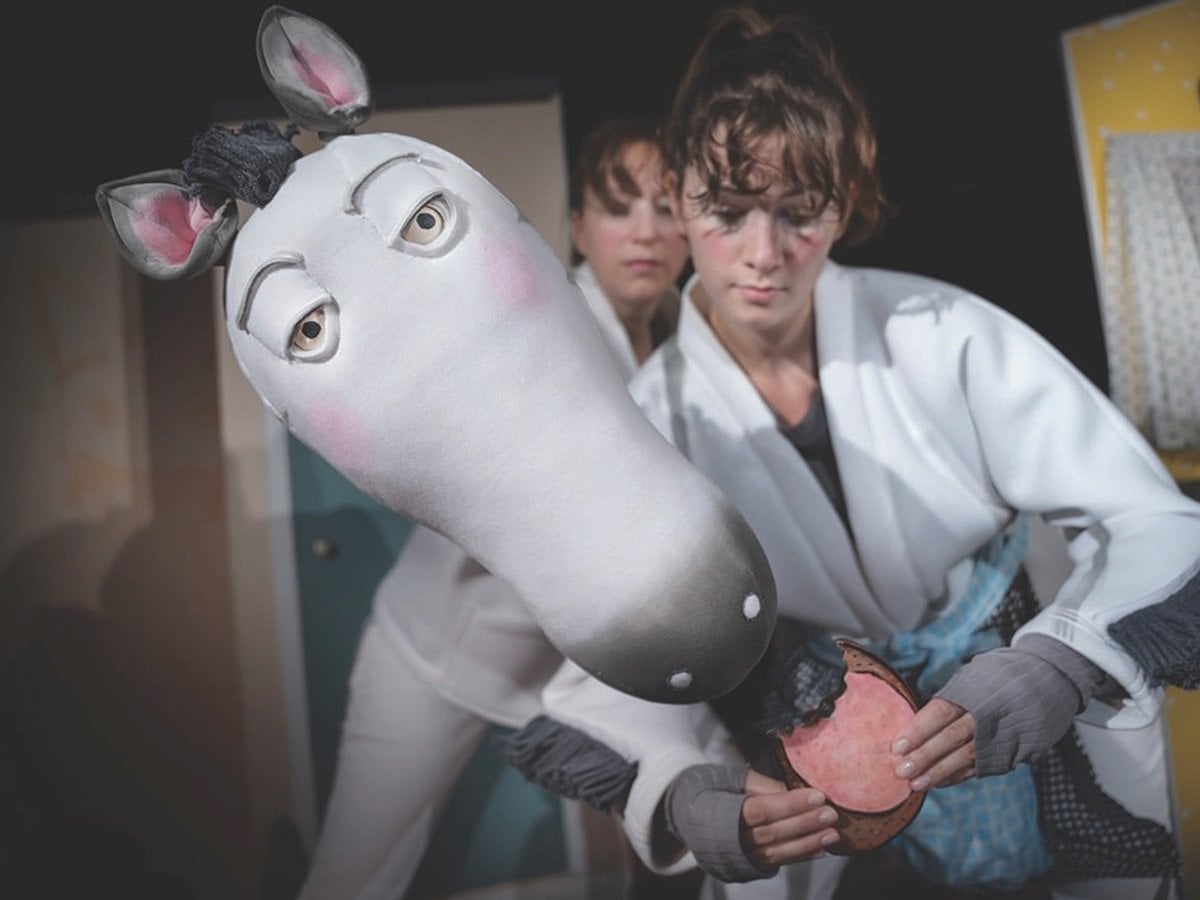 Två skådespelare på en scen med en docka föreställande en häst.