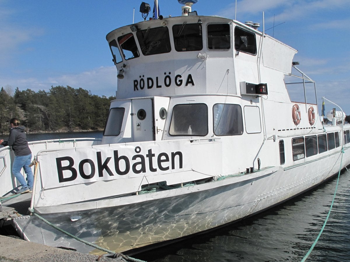 Vit båt med svart text Bokbåten ligger vid kaj.