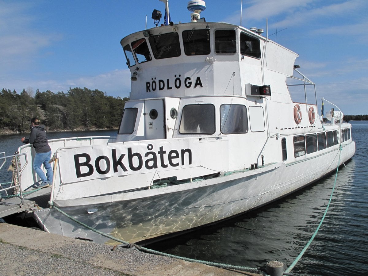 Vit båt med svart text Bokbåten ligger vid kaj.