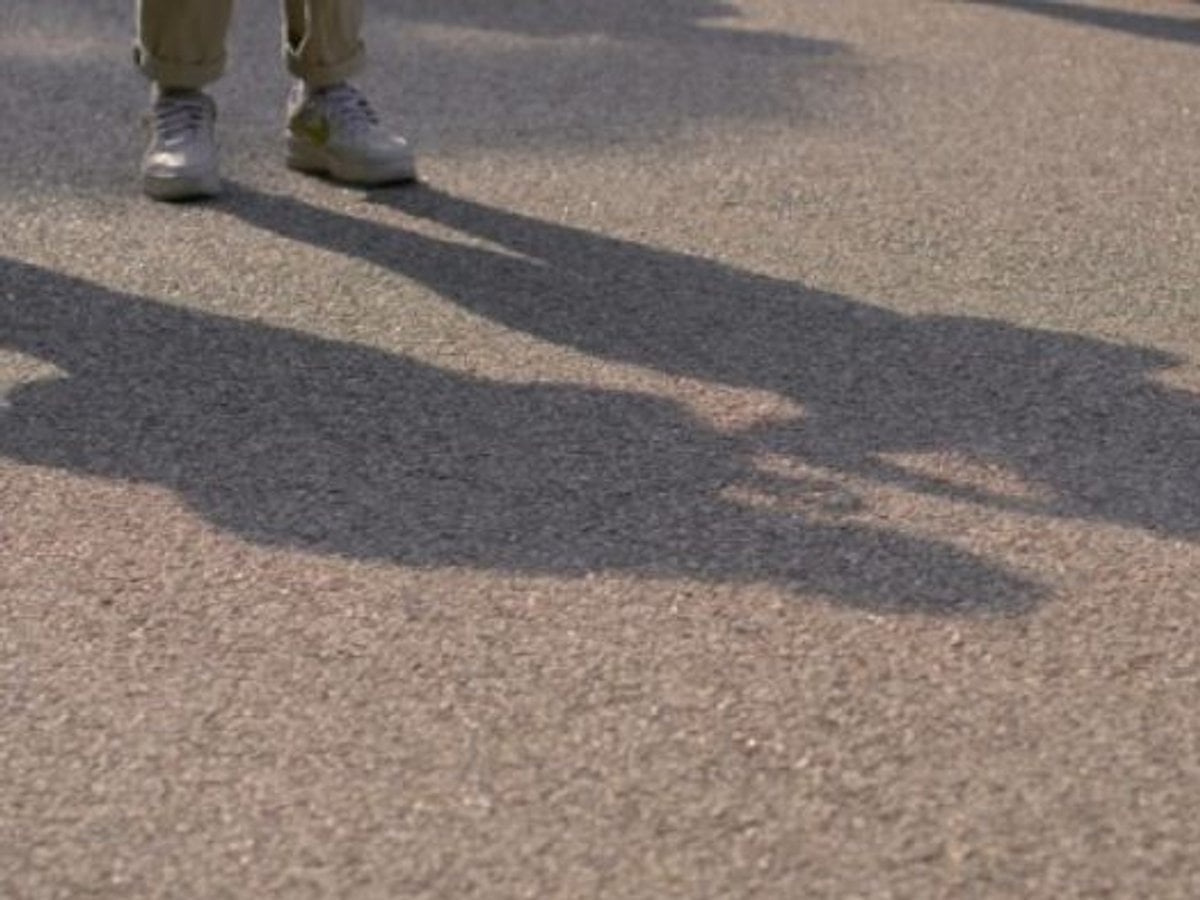 En skugga av en person som står på en gata.