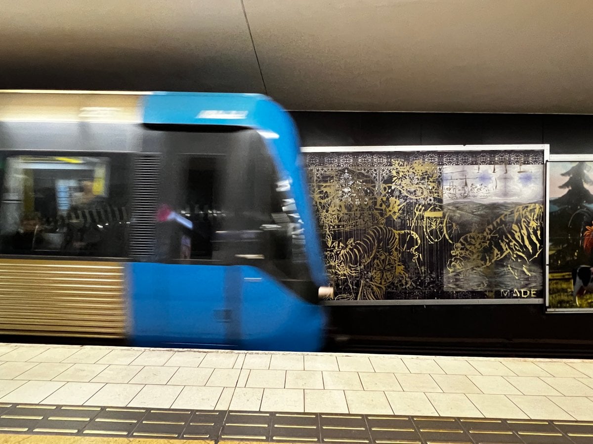 Ett blått tåg som passerar en tunnelbanestation.