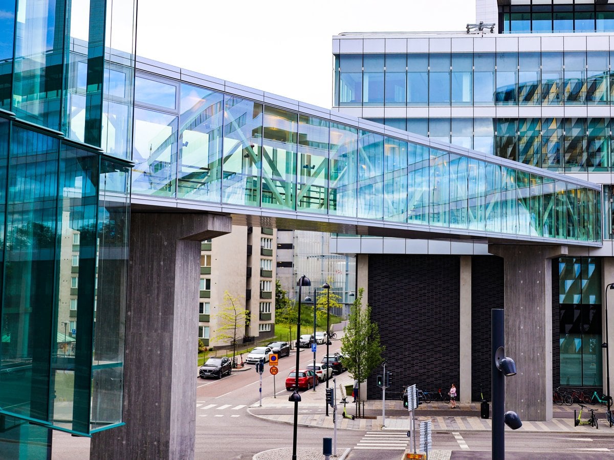 Foto på en gångbro med glasväggar mellan två byggnader.