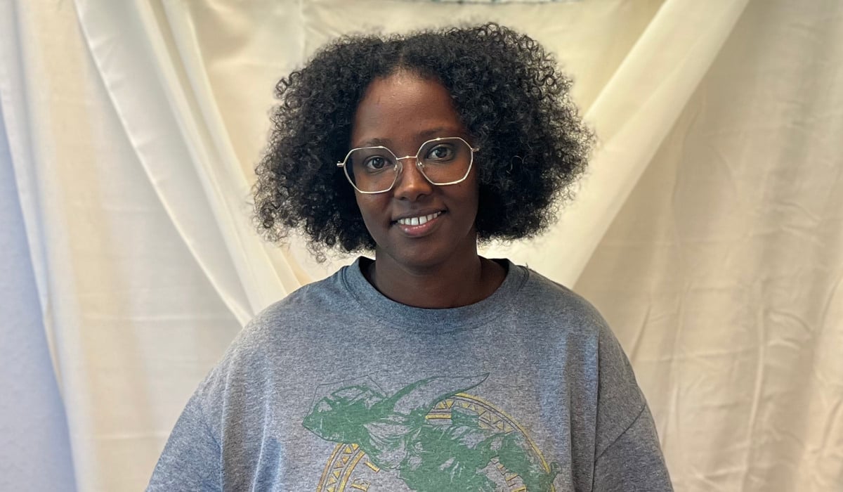 En kvinna står framför en vit gardin.