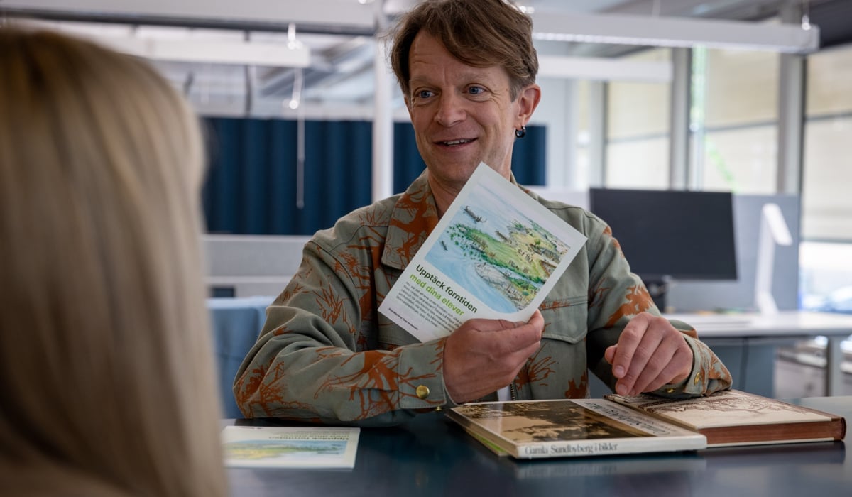En man som sitter vid ett bord och läser en bok.