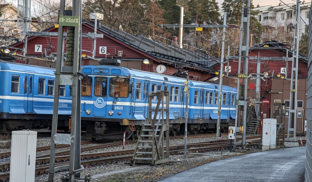 Ett blått tåg som passerar en tågstation.