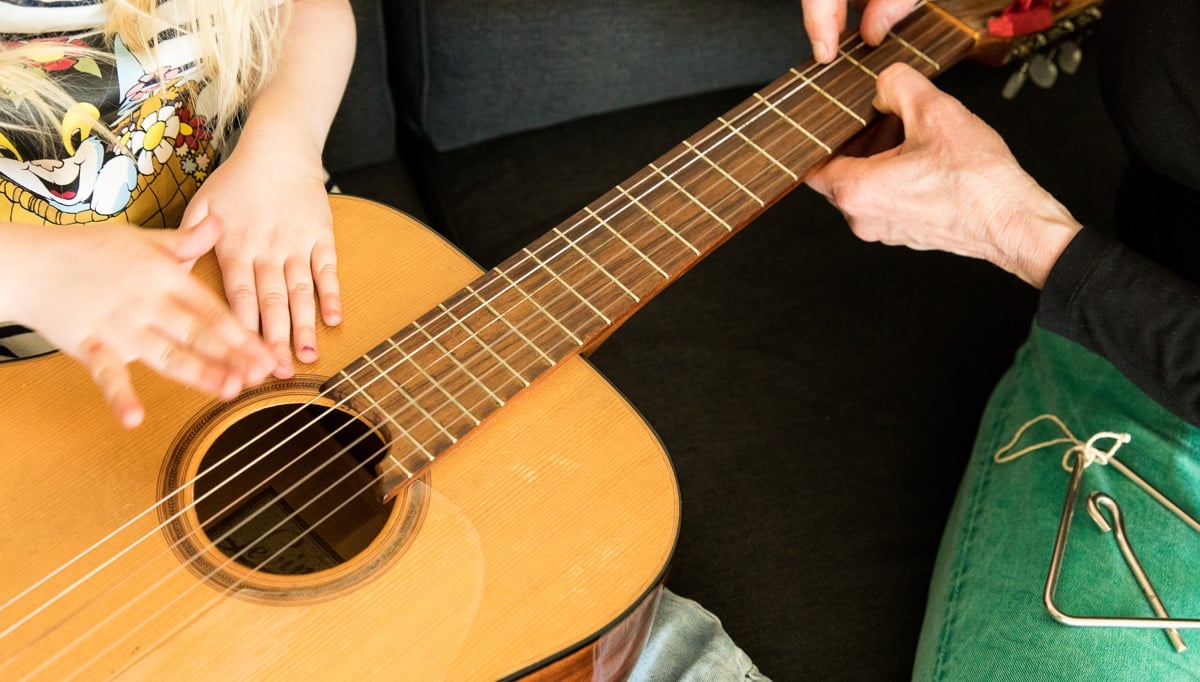 Händer som håller i en gitarr.