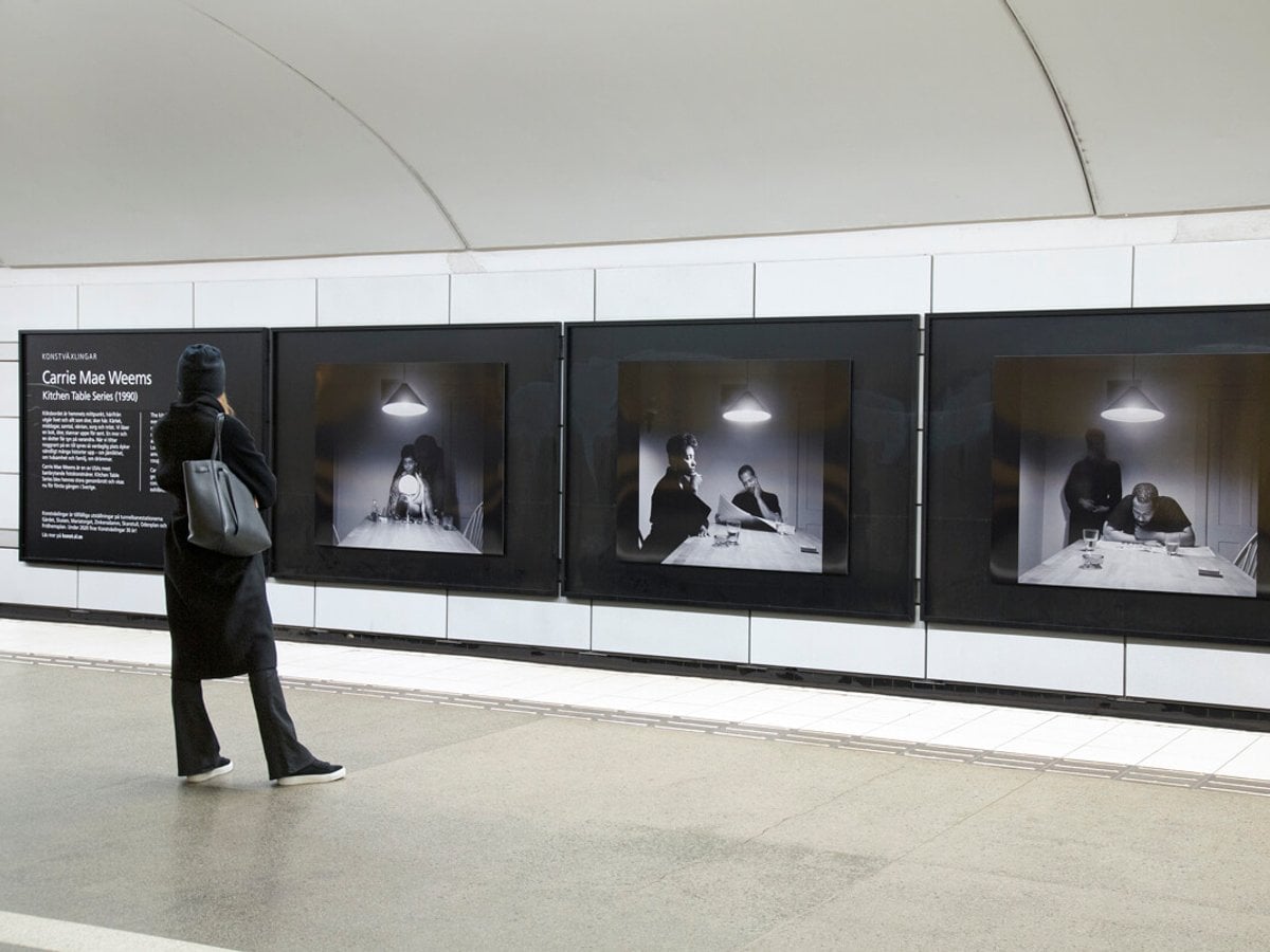 Person står på perrongen och tittar på fotoutställning på spårvägg.