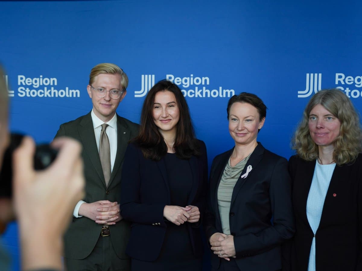 Foto på fyra politiker som står uppradade. I förgrunden syns en fotograf.