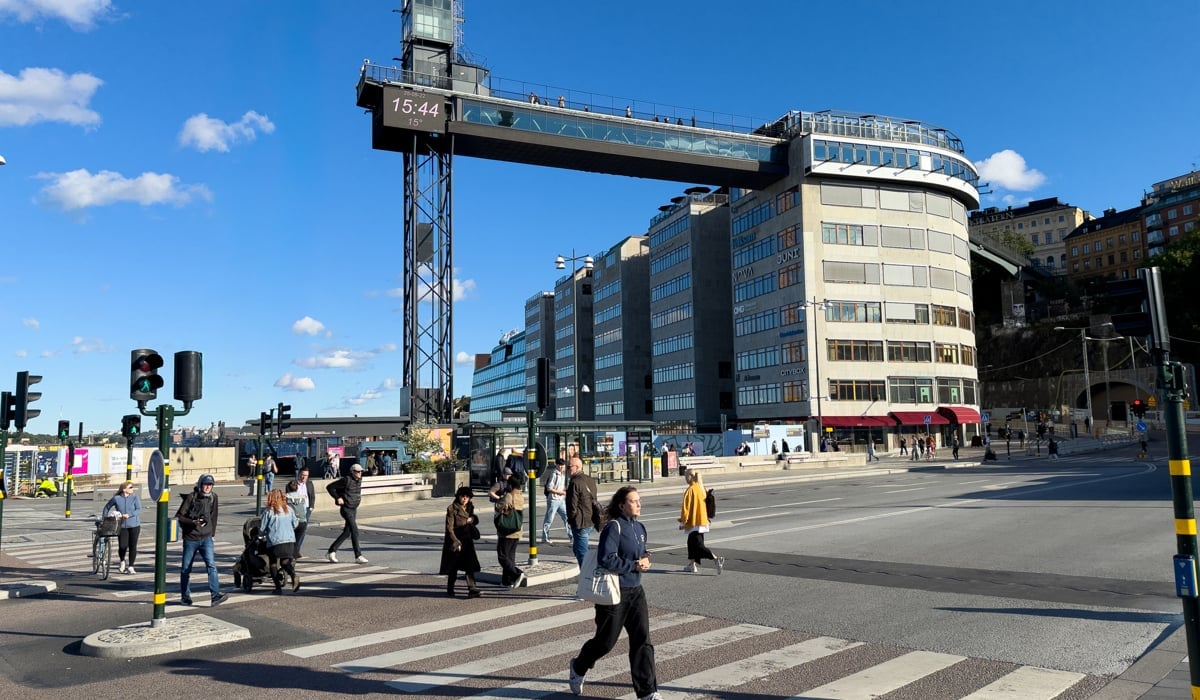 En grupp människor som korsar en gata framför en hög byggnad.